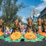Children in vibrant traditional Filipino costumes performing a cultural street dance during the Flores de Mayo festival.