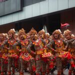 Performers in vibrant traditional costumes dancing during the Sinulog street festival.